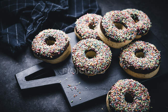 Im Ofen gebackene vegane Donuts mit dunkler Schokoladenglasur und bunten Streusel — Stockfoto
