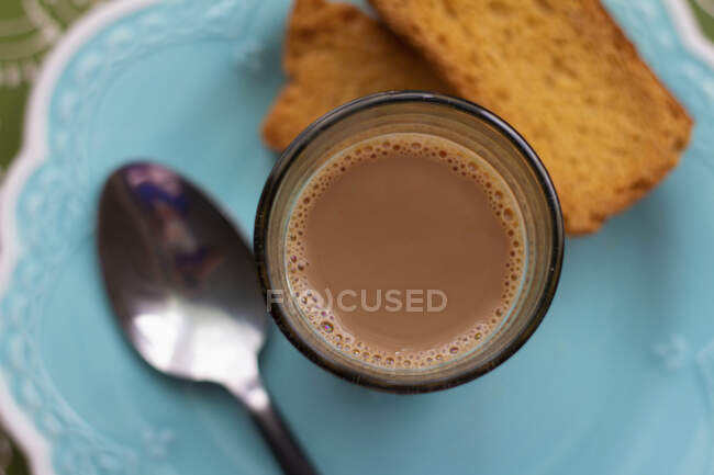 Masala Chai in vetro con biscotti e cucchiaio sul piatto — Foto stock