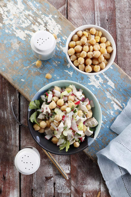 Salad with chickpeas, chicken and radish on rustic wooden surface — Stock Photo