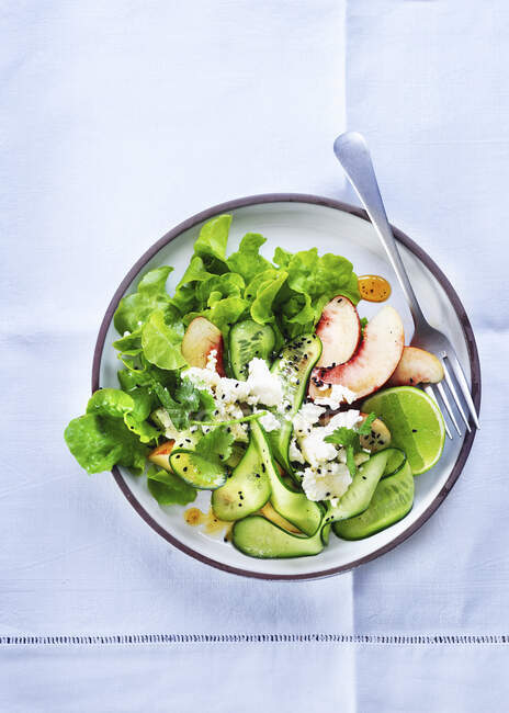 Салат з огірком, персиками, фетою та лаймом — стокове фото