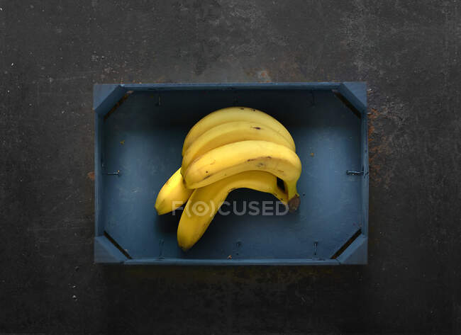 Plátanos en una caja de madera azul - foto de stock