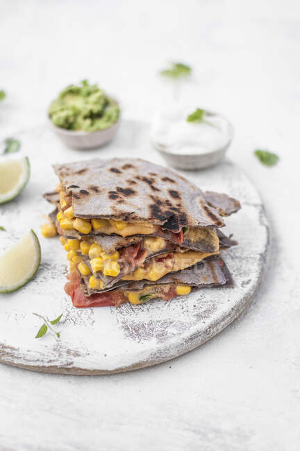 Vegane Quesadillas gefüllt mit veganer Käsesauce, Mais, Tomaten und Jalapeño, serviert mit Guacamole und Sojajoghurt — Stockfoto