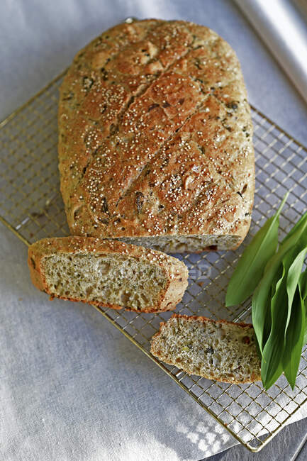 Wild garlic spelt bread on cooling rack with green leaves — Stock Photo