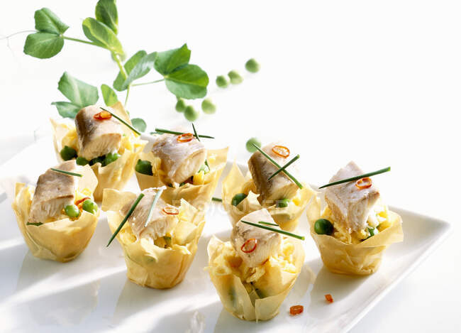 Filo pastry bowls with scrambled eggs, smoked eel, peas and chili — Foto stock