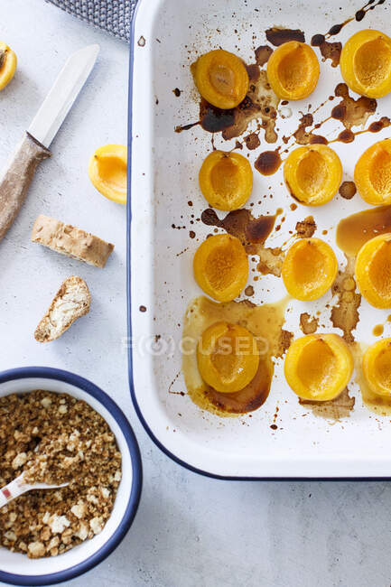 Caramelized apricots in ceramic tin with crumbles in bowl — Stock Photo