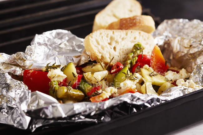 Grilled Mediterranean vegetables with a herb marinade in aluminium foil with sheep's cheese and white bread — Stock Photo