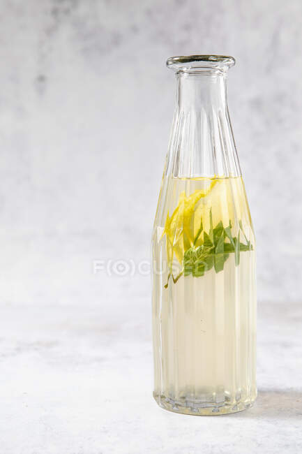 Thé à la menthe poivrée froide au citron dans une bouteille en verre — Photo de stock