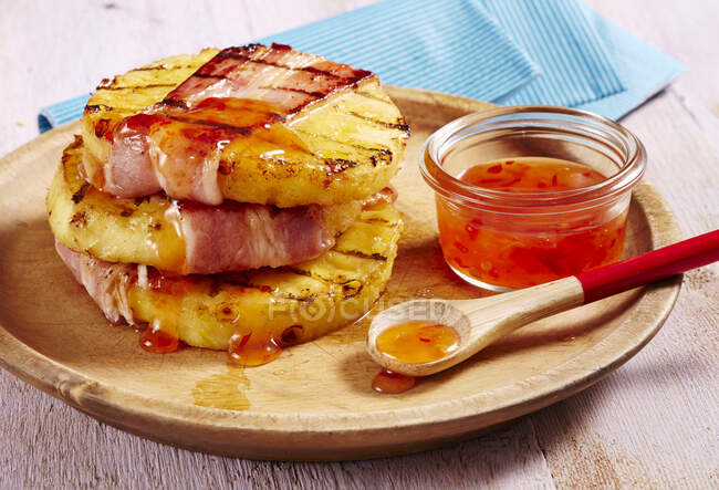 Fette di pancetta e ananas alla griglia con salsa di peperoncino dolce e piccante su piatto di legno — Foto stock
