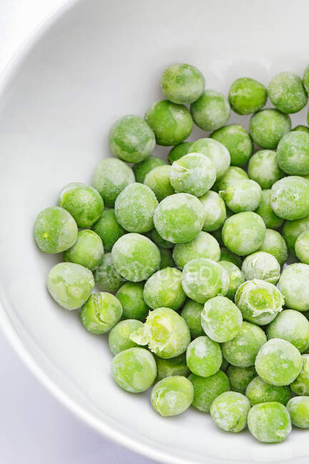 Green peas in bowl on white background — Stock Photo