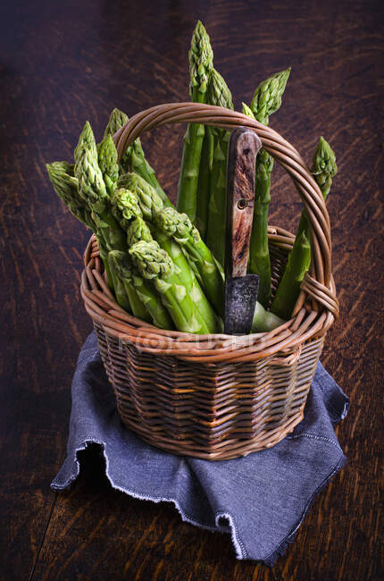 Fresh green asparagus in wooden box on dark background — Stock Photo