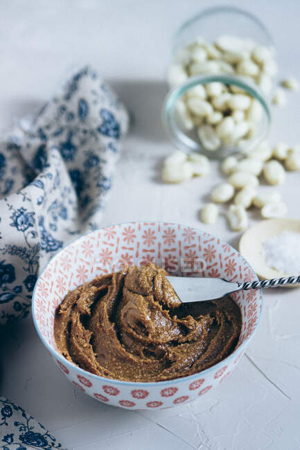 Beurre d'arachide fait maison dans un bol en céramique avec spatule métallique — Photo de stock