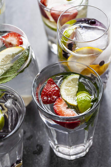 Copos de bebidas cheias de frutas, hortelã e gengibre — Fotografia de Stock