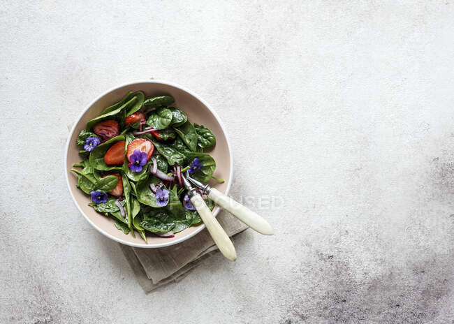 Frischer Sommersalat aus Spinat, Erdbeeren, Zwiebeln mit Balsamico-Essig und essbaren Blumen — Stockfoto