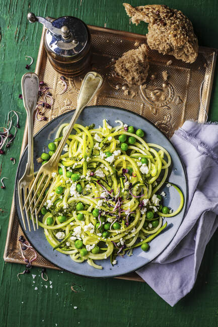 Zucchini spaghetti with feta and peas — Stock Photo