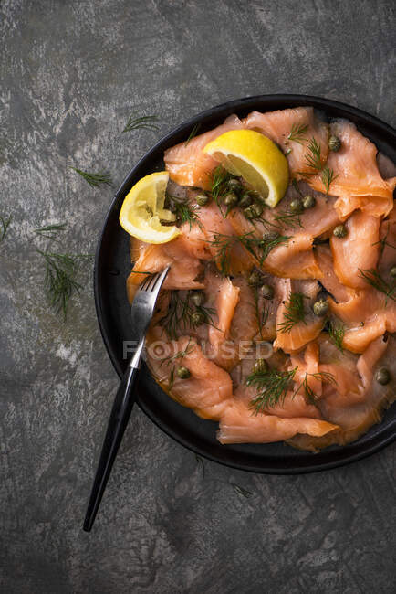Копченый лосось с каперсами, лимоном и свежим укропом — стоковое фото
