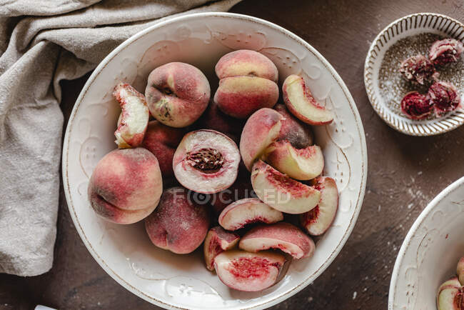 Ganze, halbierte und geschnittene Pfirsiche in Keramikschale — Stockfoto