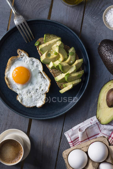 Un uovo fritto e un pane integrale con avocado a colazione — Foto stock