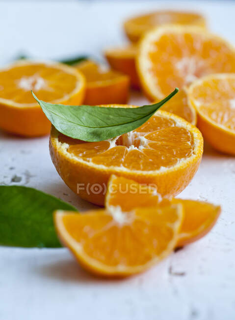 Naranjas con hojas enteras, cortadas a la mitad y rebanadas - foto de stock