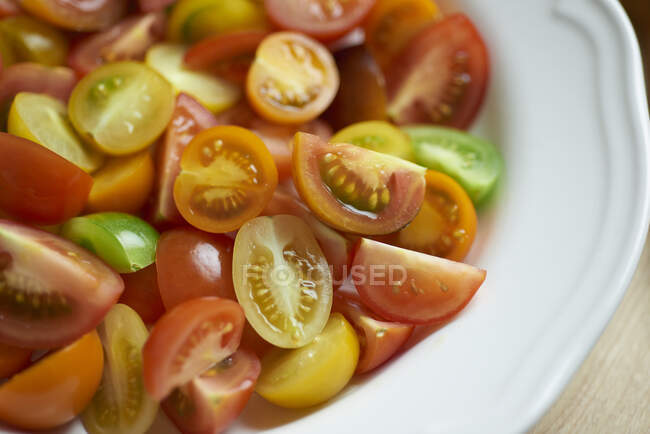 Tomates coloridos, cortados pela metade e esquartejados, sobre um prato — Fotografia de Stock