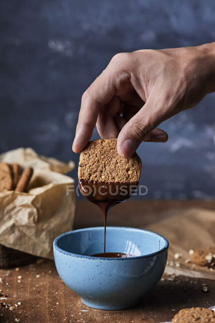 Dipping walnut cookie in melted chocolate — Stock Photo