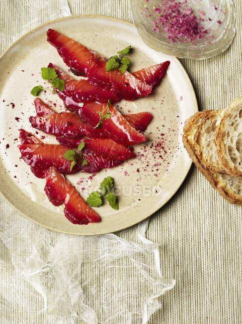 Beetroot salt cured salmon with bread slices — Stock Photo