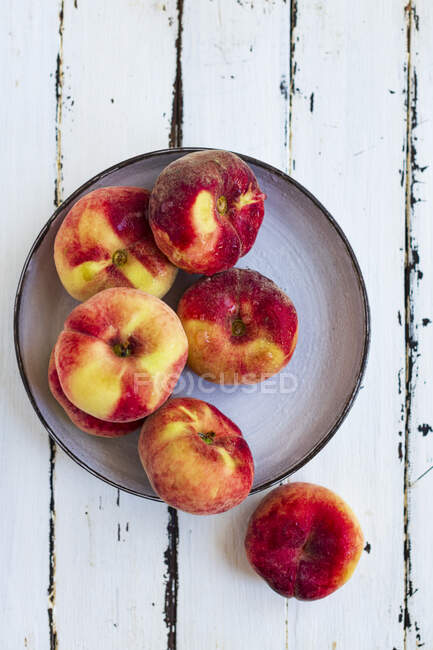 Персики на тарелке на деревенской деревянной поверхности — стоковое фото