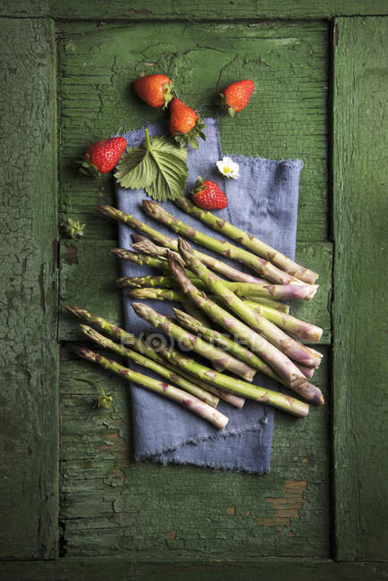 Strawberries and green asparagus on a blue linen cloth — Stock Photo