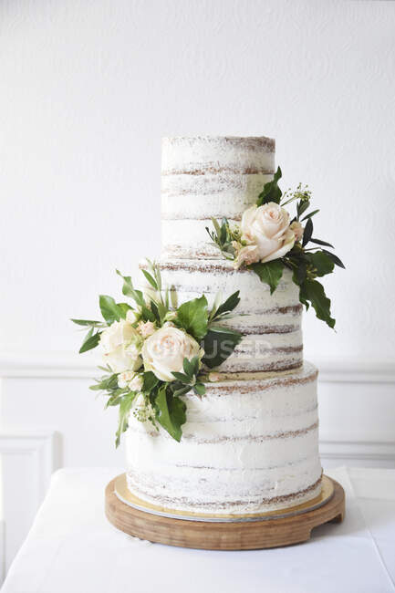 Um bolo de casamento nu de três camadas decorado com rosas — Fotografia de Stock