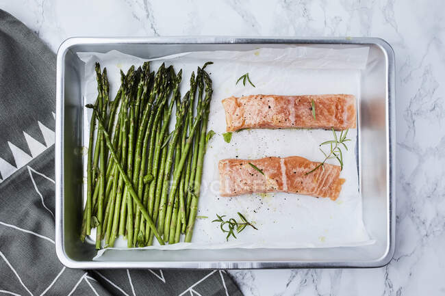 Salmon and asparagus in the pan, ready for oven, seasoned with olive oil and rosemary — Photo de stock