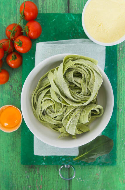 Fresh green tagliatelle with tomatoes, egg and flour — Stock Photo
