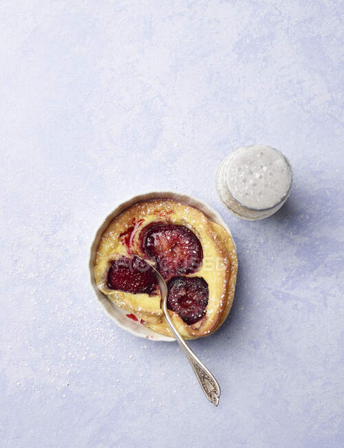Mini plum clafoutis pie with powdered sugar and fork — Stock Photo