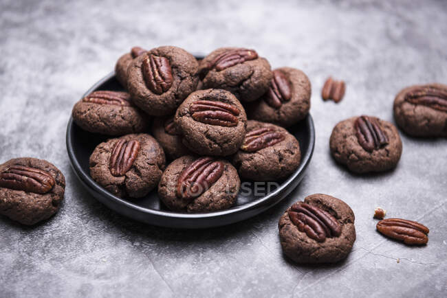 Biscotti al cioccolato di noci pecan in piatto e su superficie di pietra — Foto stock