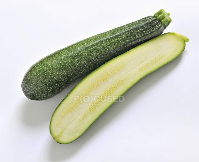 Zucchini, ganz und halbiert auf weißem Hintergrund — Stockfoto