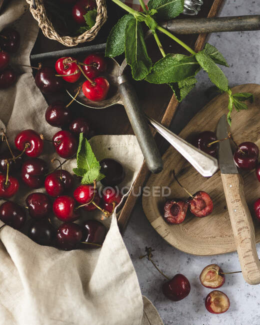 Cherries in wooden crate and plate with mint — Stock Photo