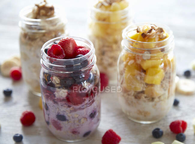 Overnight oats with raspberries, strawberries, blueberries, bananas and mango in jars — Stock Photo