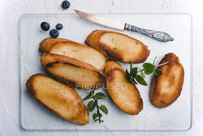 Fette di baguette tostate con margarina, menta e mirtilli — Foto stock