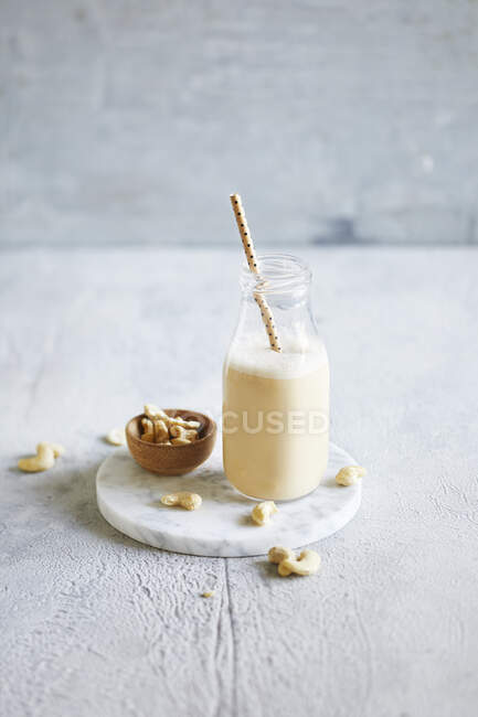 Cashew milk in a glass bottle and nuts — Stock Photo