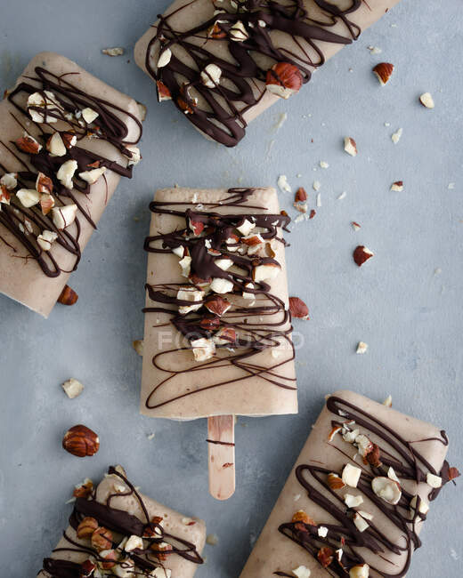 Banana and peanut butter ice cream sticks with chocolate and chopped nuts — Stock Photo