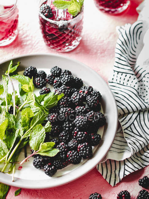 Blackberries and mint leaves on white plate — Stock Photo