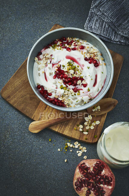 Bowl of pomegranate granola with yoghurt on wooden board — Stock Photo