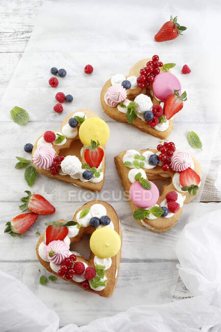 Heart shaped cakes with meringues, berries and mini macarons — Stock Photo