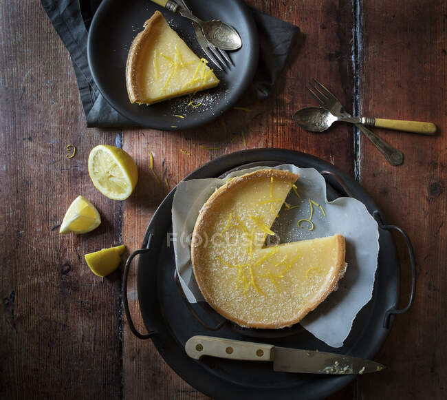 Tarta de limón con rebanada sacada Rebanada en plato con limones - foto de stock