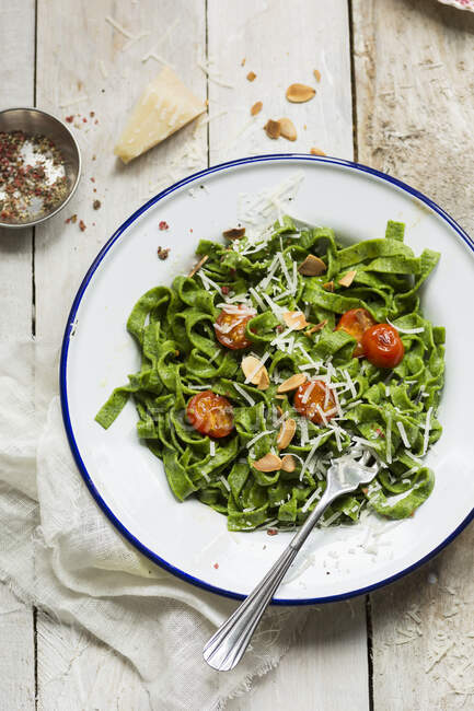 Spinatnudeln mit Tomaten, Parmesan und gerösteten Mandeln — Stockfoto