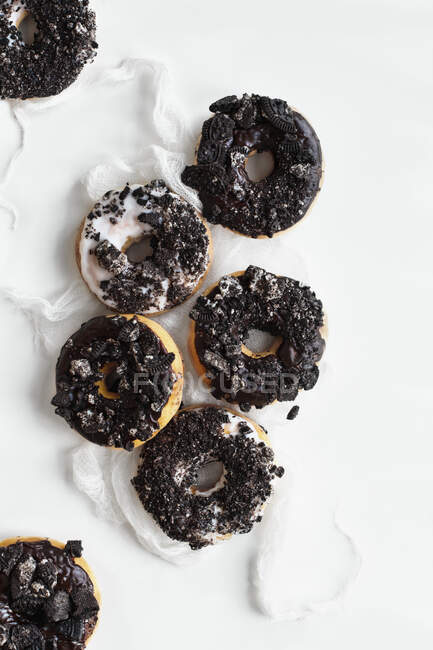 Donuts with vanilla and chocolate icing and Oreo cookie crumbs — Stock Photo