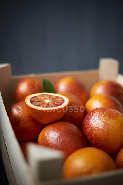 Arance rosse in scatola di legno, una dimezzata — Foto stock