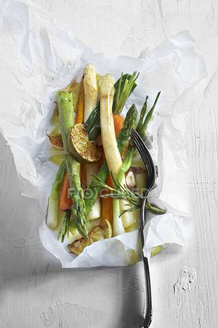 Verduras en papel pergamino con romero y limas - foto de stock