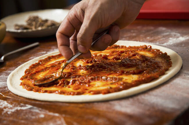 Tomatensauce zur Pizza hinzufügen — Stockfoto