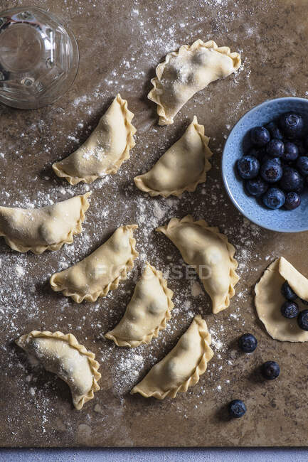Homemade ravioli with fresh blueberries and flour on table — Stock Photo