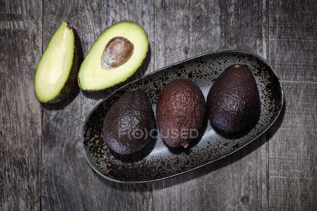 Avocados in und neben einer Keramikschale — Stockfoto