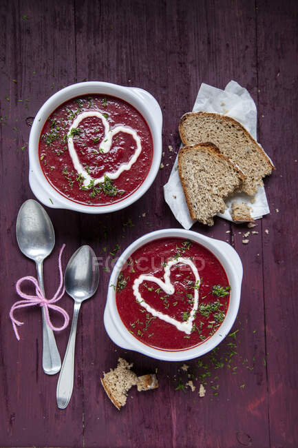 Beetroot soup garnished with yoghurt hearts and dill — Stock Photo